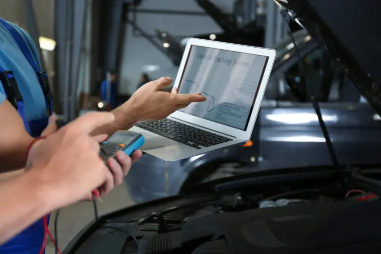 Mechaniker liest mit einem Laptop den Fehlerspeicher eines Fahrzeugs aus