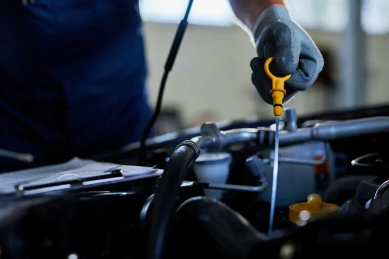 Hand prüft mit dem Ölmessstab den Ölstand am Motor
